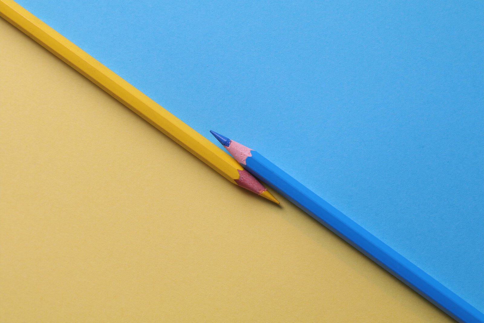 A creative design of one yellow and one blue pencil with yellow and blue background